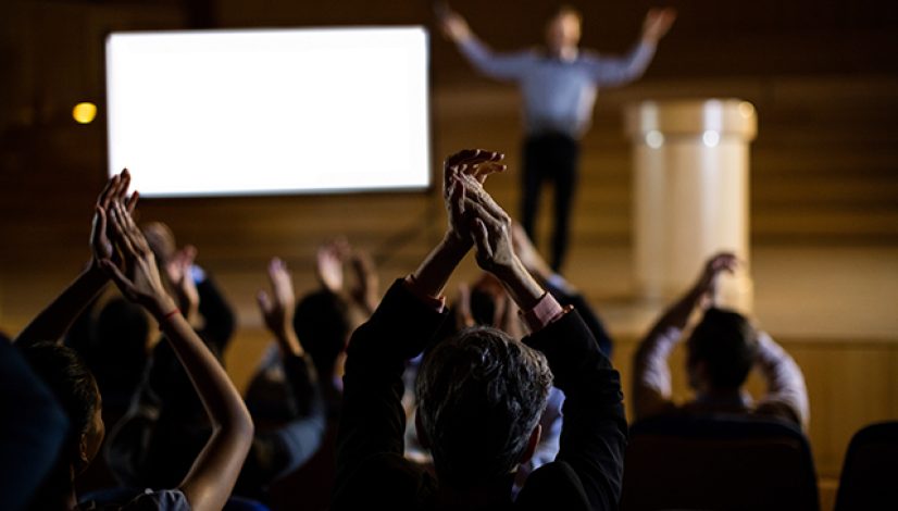 Audience applauding speaker after conference presentation at conference center